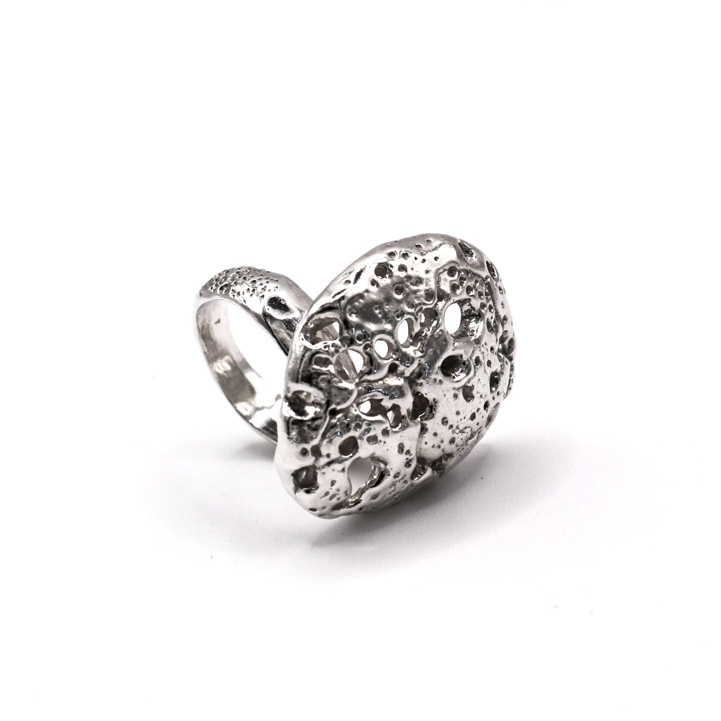 Sculptural silver ring with organic texture inspired by hag stones, handmade in Valencia. Anillo escultórico de plata con textura orgánica inspirado en piedras agujereadas, hecho a mano en Valencia