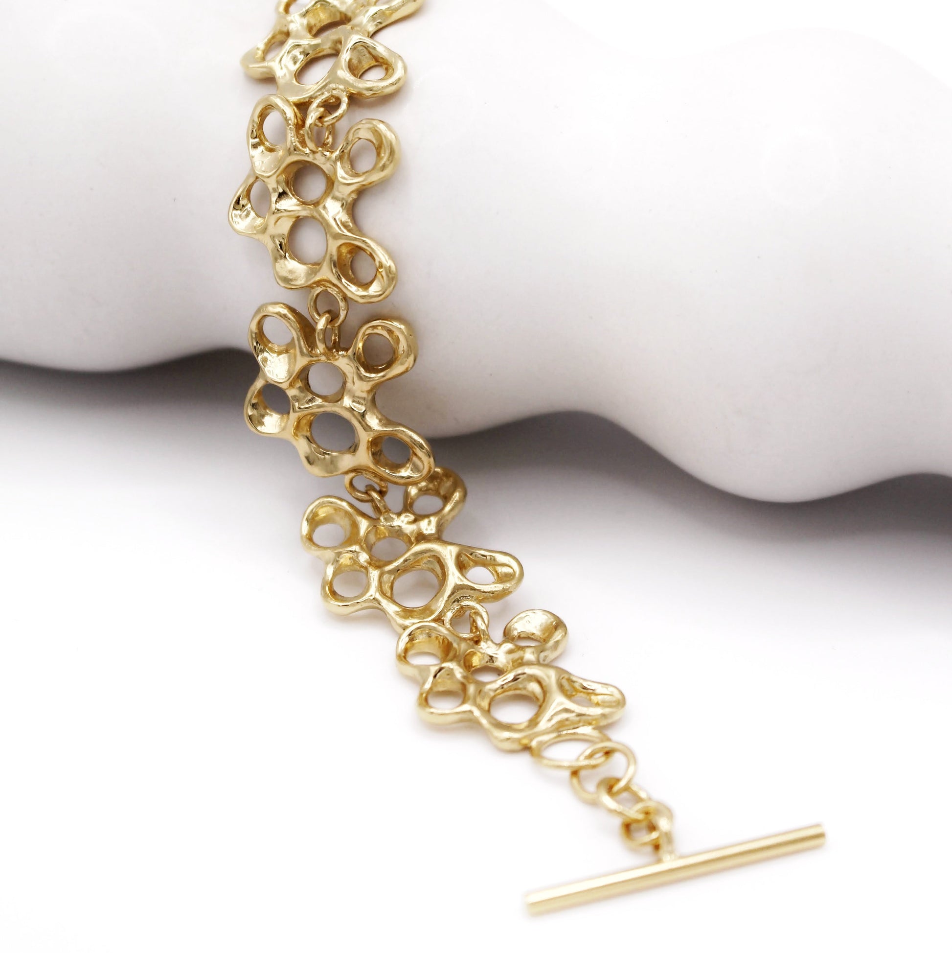 Raíz bracelet handcrafted in sterling silver with a gold-plated finish. Mediterranean-inspired jewelry formed of nine organic-shaped segments with a stylish toggle clasp. A bold yet elegant sustainable bracelet for nature and contemporary jewelry lovers, crafted by Naturalesa.