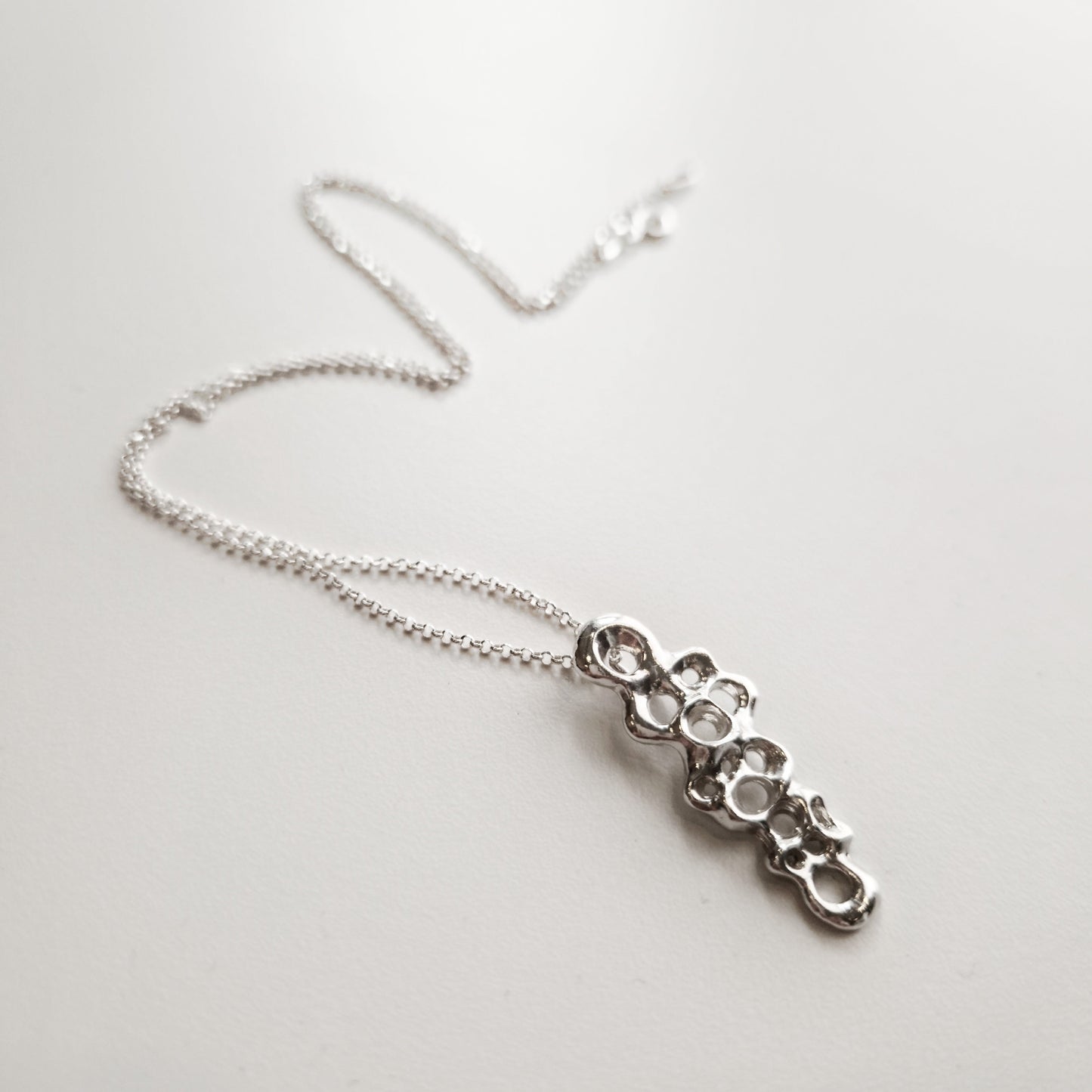 Slim Raíz Necklace, sculptural silver pendant symbolizing resilience and inner strength.
Collar Raíz Slim, colgante escultural en plata que simboliza resiliencia y fuerza interior.