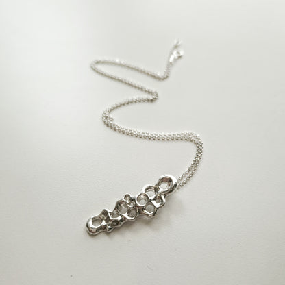 Silver necklace with a unique pendant on a white background.Raíz Slim Pendant in recycled sterling silver 925 with diamond rolo chain, minimalist sea inspired necklace. Colgante Raíz Slim en plata reciclada 925 con cadena rolo diamante, collar minimalista inspirado en el mar.